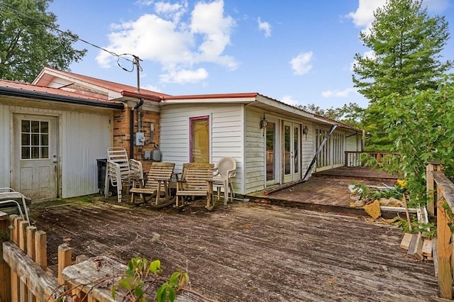 back of house featuring metal roof and a wooden deck