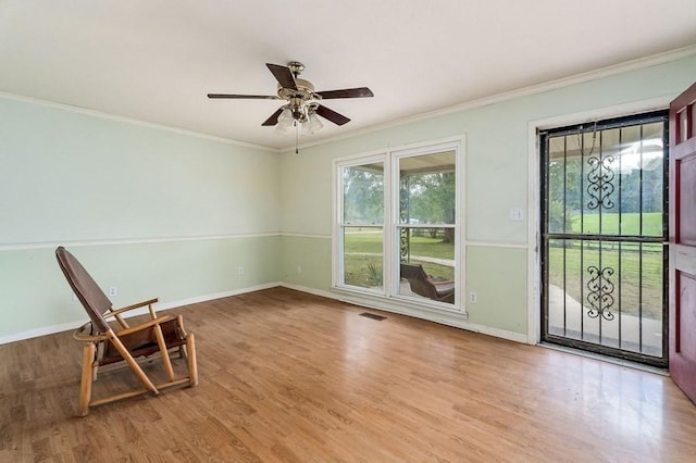 unfurnished room with crown molding, visible vents, a ceiling fan, wood finished floors, and baseboards