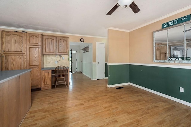 interior space with ceiling fan, visible vents, ornamental molding, brown cabinets, and light wood finished floors