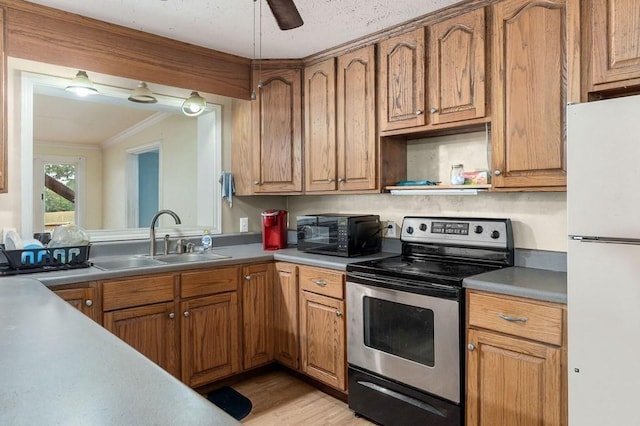 kitchen featuring ornamental molding, brown cabinets, freestanding refrigerator, stainless steel range with electric stovetop, and a sink