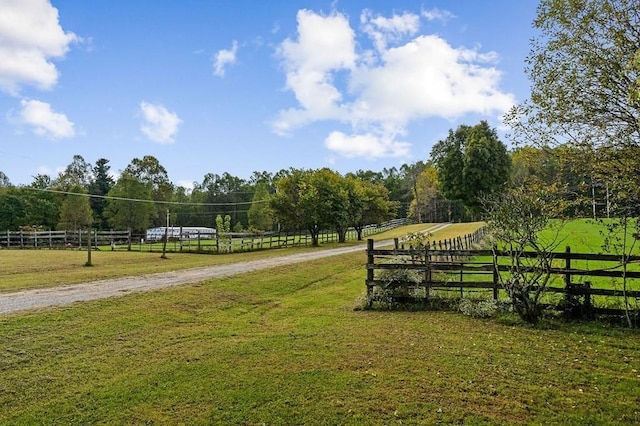 view of property's community with a yard, a rural view, and fence