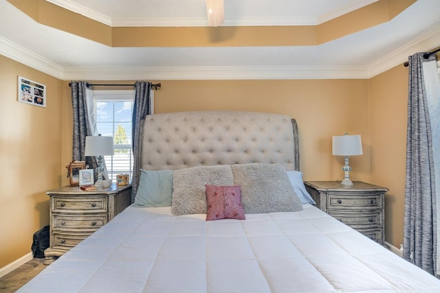 bedroom featuring baseboards, a raised ceiling, and crown molding