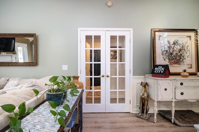 entryway featuring french doors, a wainscoted wall, and light wood finished floors