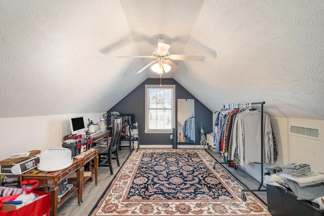 office area with visible vents, ceiling fan, vaulted ceiling, a textured ceiling, and wood finished floors