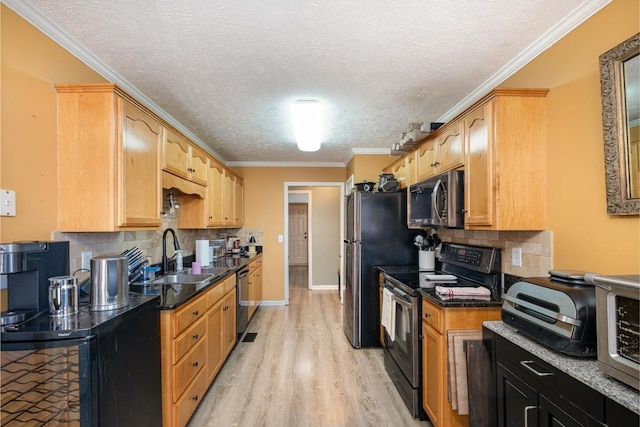 kitchen featuring a breakfast bar, crown molding, light wood finished floors, a sink, and black appliances