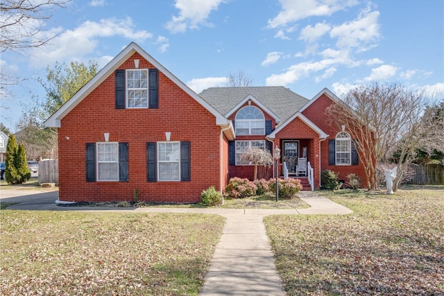 traditional-style house featuring brick siding, a front yard, and fence