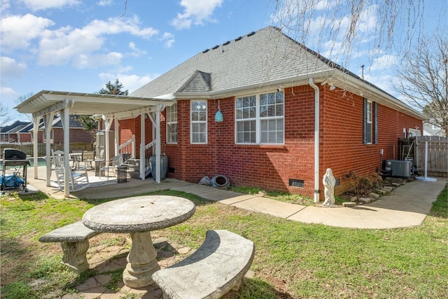 rear view of property with brick siding, a yard, a patio, crawl space, and fence