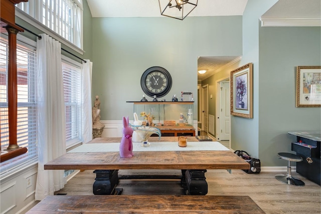 dining area with light wood finished floors, baseboards, a high ceiling, and ornamental molding