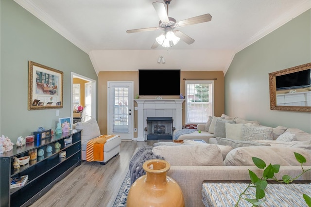 living area featuring light wood-style floors, vaulted ceiling, ceiling fan, and ornamental molding