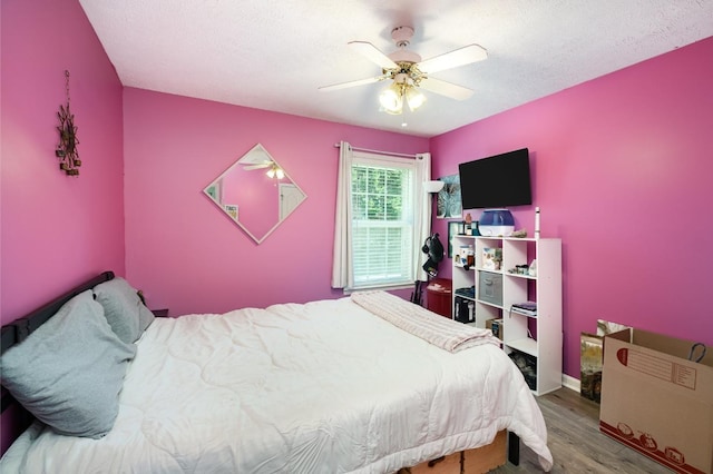 bedroom with ceiling fan, a textured ceiling, and wood finished floors