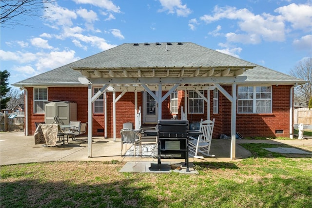 rear view of property featuring an outbuilding, brick siding, roof with shingles, a storage unit, and crawl space