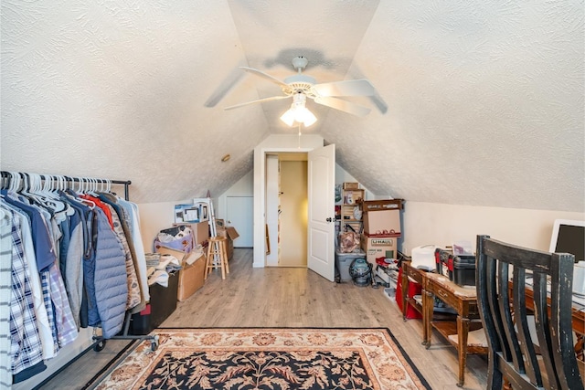 bonus room with lofted ceiling, light wood-style floors, ceiling fan, and a textured ceiling