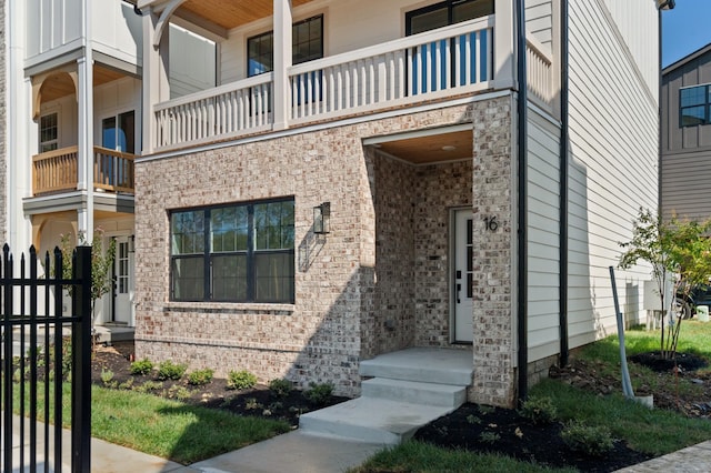 entrance to property featuring brick siding and fence