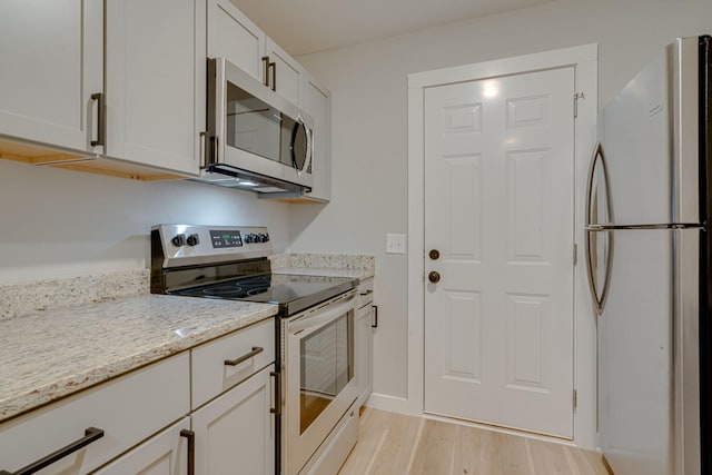 kitchen with stainless steel appliances, light wood-type flooring, white cabinets, and light stone countertops