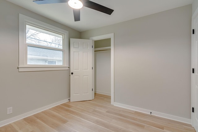 unfurnished bedroom with light wood finished floors, a closet, baseboards, and a ceiling fan