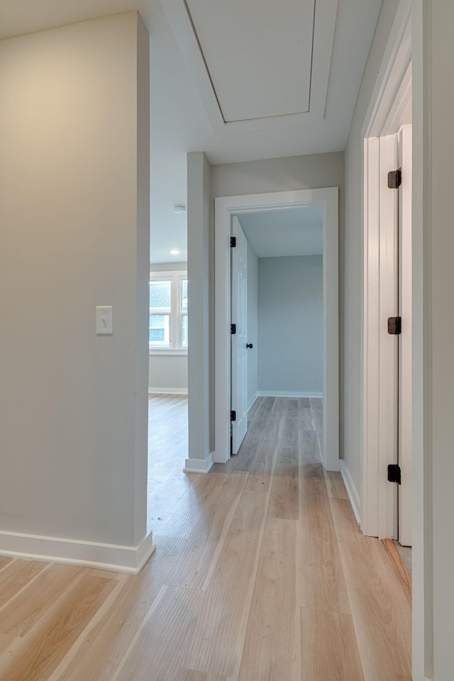 hall with light wood-style flooring and baseboards