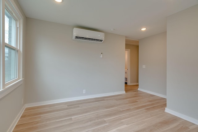 unfurnished room with light wood-type flooring, recessed lighting, baseboards, and a wall mounted air conditioner