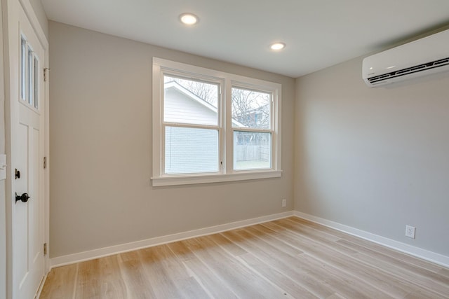 empty room featuring light wood finished floors, recessed lighting, baseboards, and a wall mounted AC