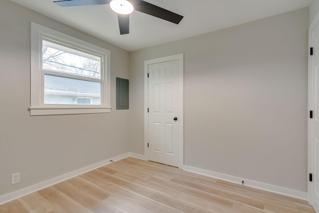 unfurnished room featuring light wood-style floors, a ceiling fan, electric panel, and baseboards