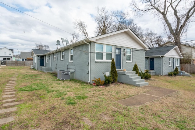 bungalow with entry steps, brick siding, fence, and a front yard