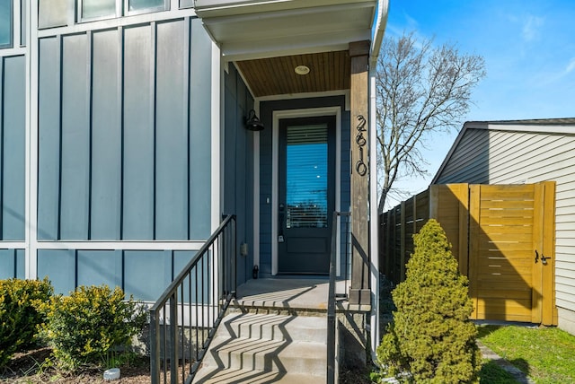 view of exterior entry with fence and board and batten siding