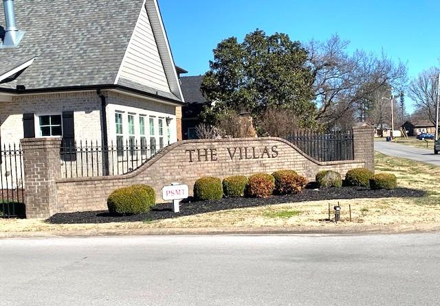 community / neighborhood sign featuring fence