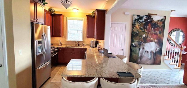 kitchen with light stone counters, a breakfast bar, a sink, a peninsula, and stainless steel fridge with ice dispenser