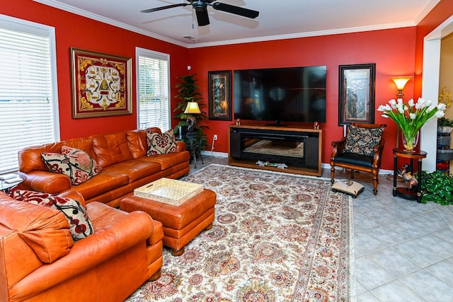 tiled living area with baseboards, ornamental molding, a ceiling fan, and a glass covered fireplace