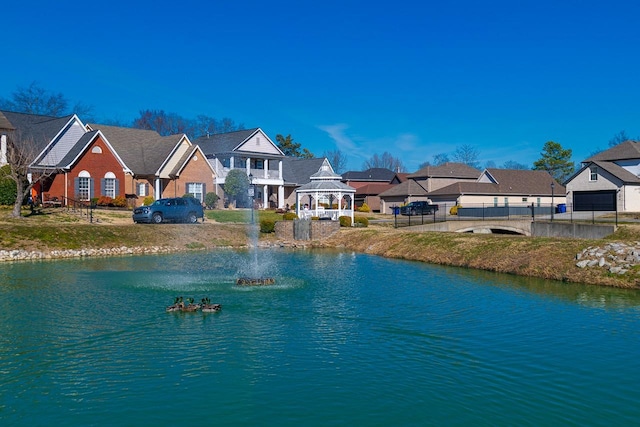 view of water feature with a residential view, fence, and a gazebo