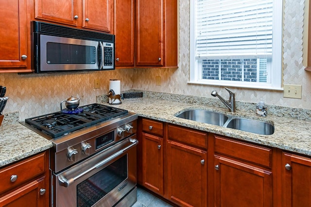 kitchen with tile patterned flooring, light stone countertops, a sink, appliances with stainless steel finishes, and decorative backsplash