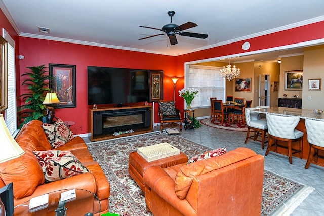 tiled living area featuring visible vents, ornamental molding, a glass covered fireplace, baseboards, and ceiling fan with notable chandelier