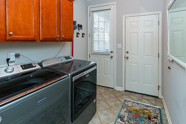 laundry room with cabinet space, baseboards, light tile patterned flooring, and independent washer and dryer