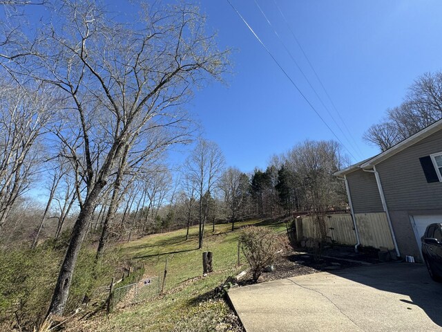 view of yard with driveway, an attached garage, and fence