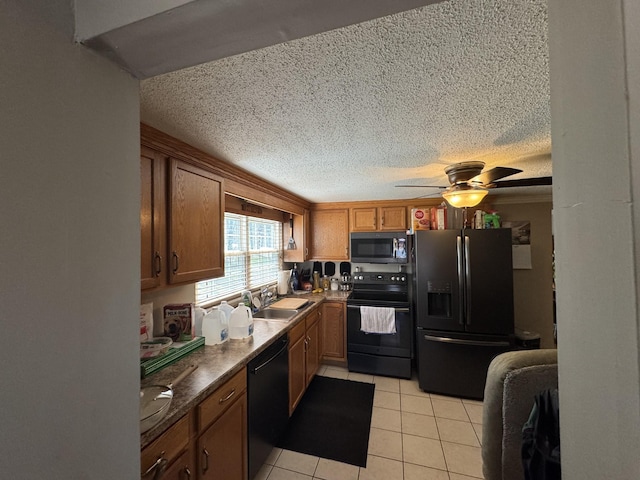 kitchen featuring light tile patterned floors, a ceiling fan, a sink, black appliances, and a textured ceiling