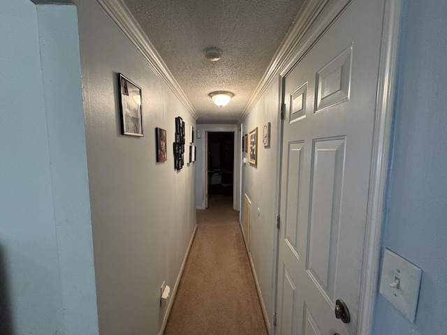 hallway featuring baseboards, light colored carpet, ornamental molding, and a textured ceiling