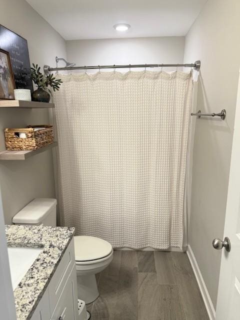 bathroom with toilet, a shower with shower curtain, wood finished floors, vanity, and baseboards