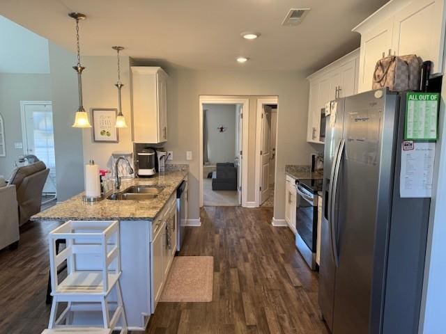 kitchen featuring appliances with stainless steel finishes, white cabinets, a sink, and decorative light fixtures