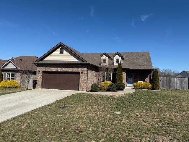 view of front of property with a garage, driveway, a front lawn, and fence