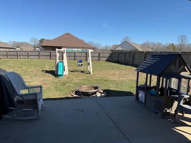 view of patio with a fire pit, a playground, and a fenced backyard