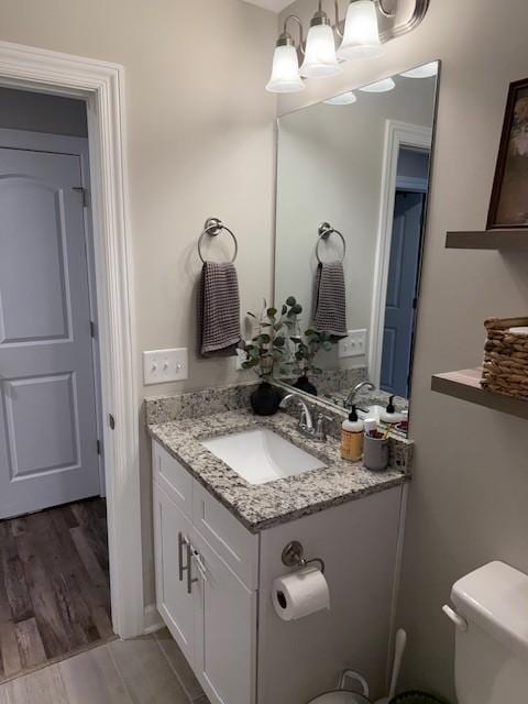 bathroom with toilet, wood finished floors, and vanity