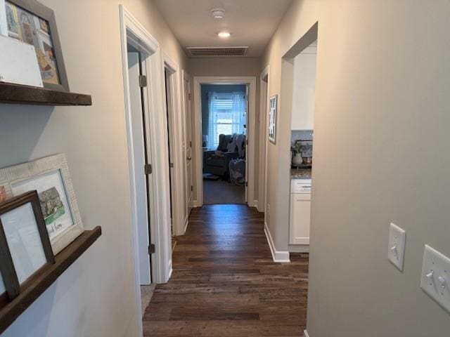 hallway with visible vents, dark wood finished floors, and baseboards