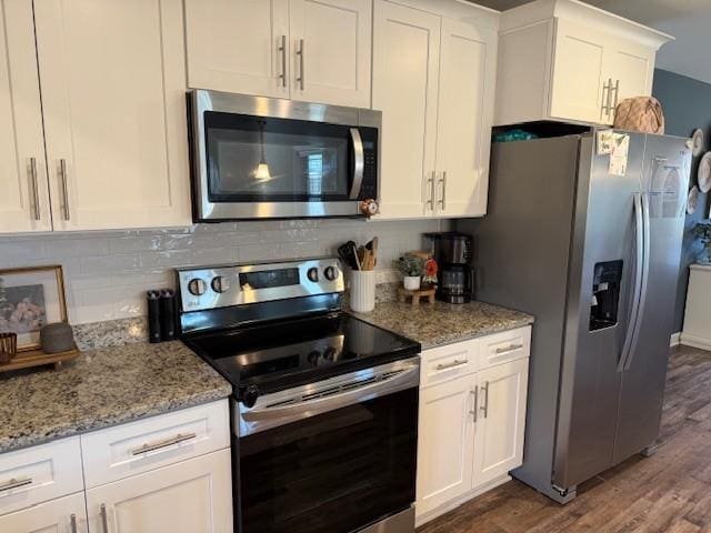 kitchen with dark wood finished floors, tasteful backsplash, appliances with stainless steel finishes, white cabinetry, and light stone countertops