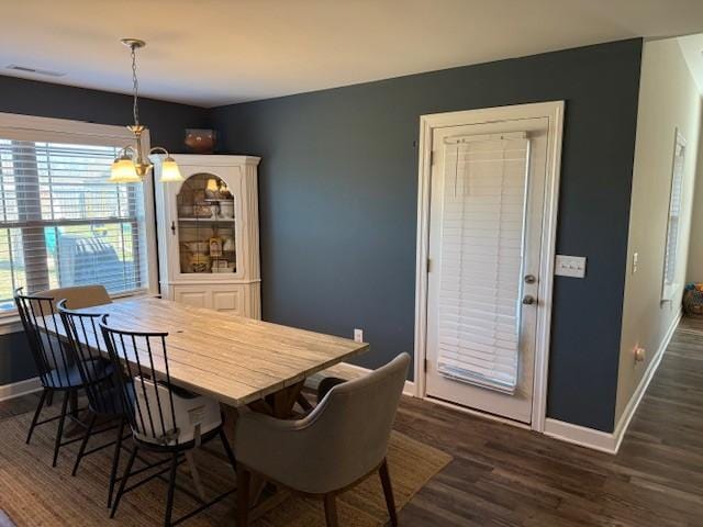 dining space with baseboards, dark wood finished floors, and a notable chandelier