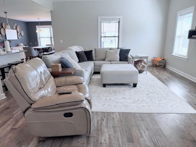 living room with a healthy amount of sunlight, dark wood finished floors, baseboards, and an inviting chandelier