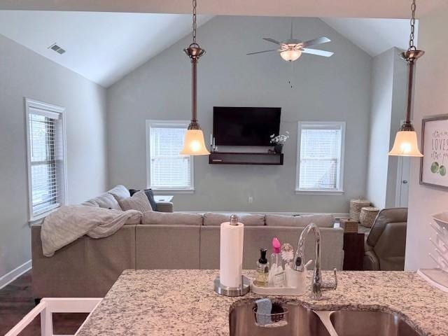 kitchen featuring pendant lighting, open floor plan, and light stone countertops