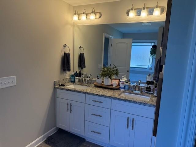 full bath with double vanity, a sink, and baseboards