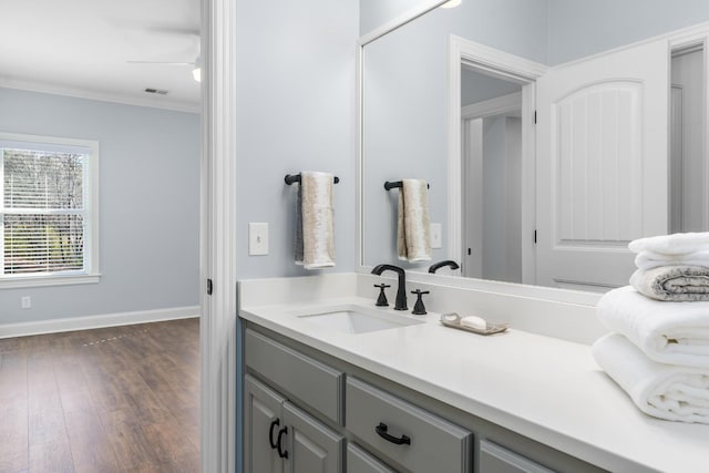 bathroom with visible vents, ornamental molding, vanity, wood finished floors, and baseboards