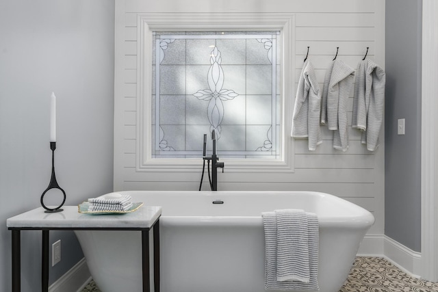 bathroom featuring a soaking tub and baseboards