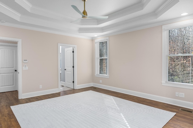 unfurnished bedroom with dark wood-style floors, a tray ceiling, visible vents, and ornamental molding