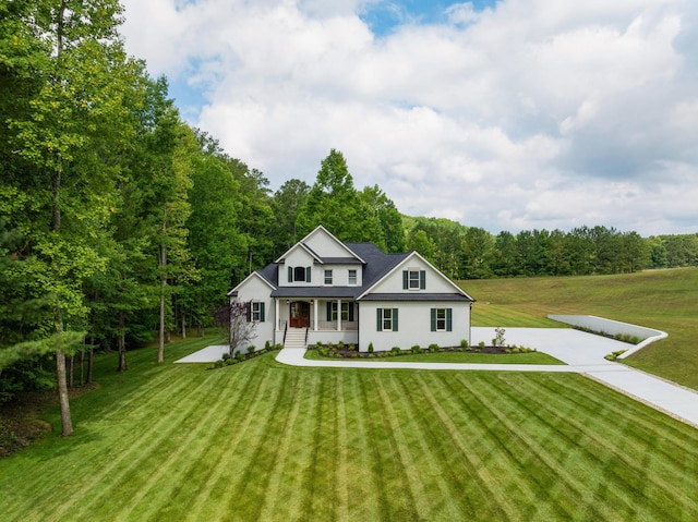 view of front of home with covered porch, a view of trees, and a front yard